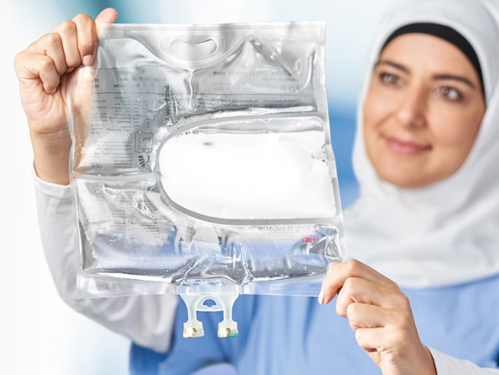 A female healthcare professional wearing a hijab is holding a 3-chamber bag