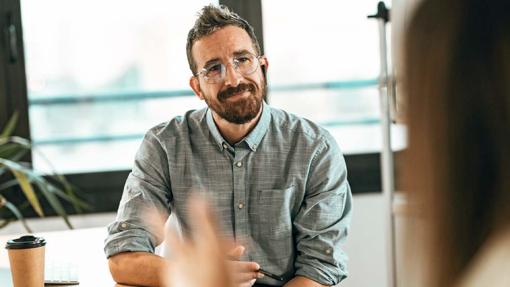 Two people are having a casual conversation in a meeting room, sharing inspiring stories. 